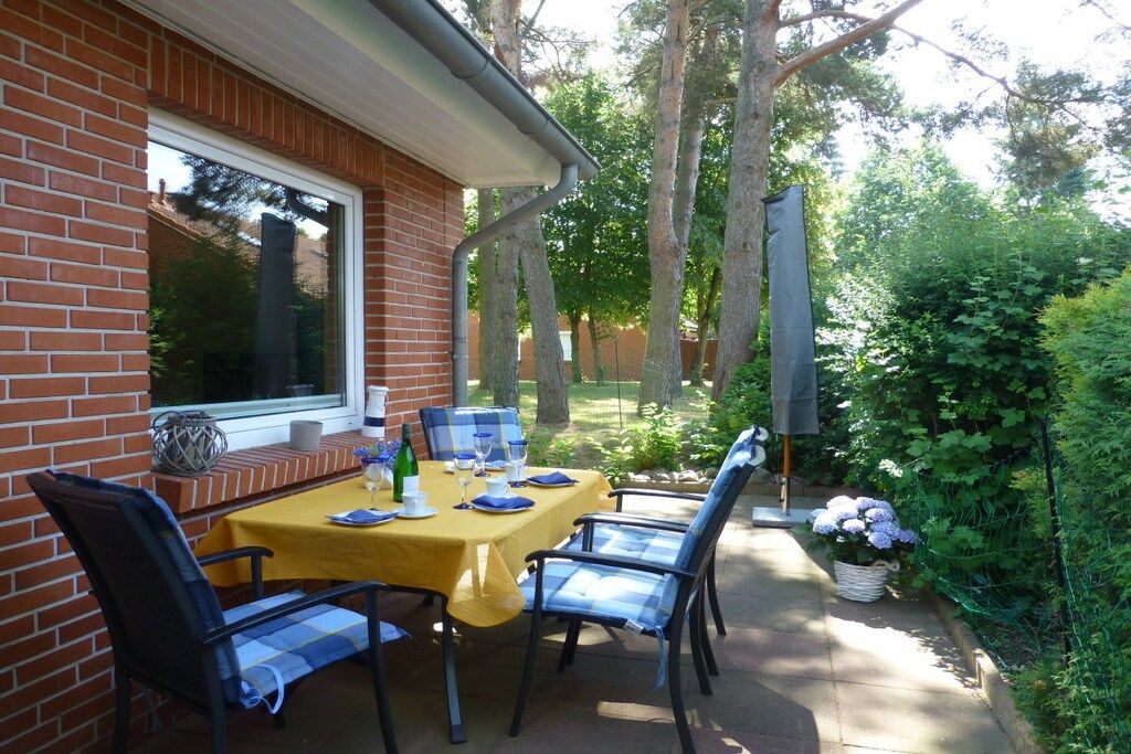 An outdoor patio with a brick wall, a yellow table set for dining, and blue chairs.