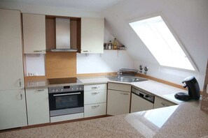 A compact kitchen with a built-in oven, a dishwasher, and a window above the sink. - Holiday apartment with 2 bedrooms (Timmendorfer Strand)