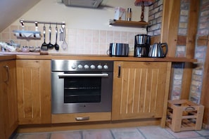 A kitchen with wooden cabinets, a stainless steel oven, and a hanging utensil rack. - at the gateway to Fischland (Ribnitz-Damgarten)