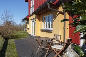 A yellow building with a red roof, a paved patio, and outdoor furniture. - Holiday apartment in Wieck with swimming pool (Wieck)