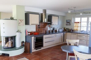 A modern kitchen with a built-in oven, a stove, and a dining area with a table and chairs. - Holiday apartment in Wieck with swimming pool (Wieck)