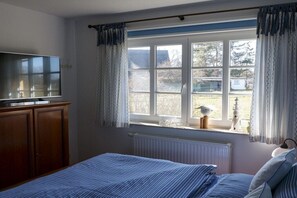 A bedroom with a bed, a dresser, a television, and a window with curtains. - Holiday apartment in Wieck with swimming pool (Wieck)