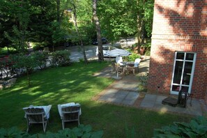 A backyard with a brick house, two lawn chairs, a table, and a covered patio area. - Buchholzer Steinbachtal (Buchholz)