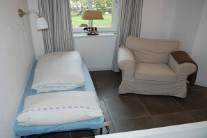 A small room with a bed, a chair, a lamp, and a window with curtains. - Buchholzer Steinbachtal (Buchholz)