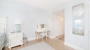 A bedroom with a bed, bedside table, lamp, vanity with mirror, and closet. - #402 Sandcastle 2/2 Oceanfront Condo Traffic Free Beach (Ponce Inlet)