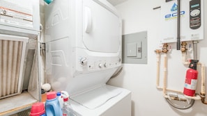 A laundry room with a white washing machine, a water heater, and a fire extinguisher. - #402 Sandcastle 2/2 Oceanfront Condo Traffic Free Beach (Ponce Inlet)