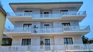 Un immeuble résidentiel à plusieurs étages, doté de balcons, de fenêtres et de climatiseurs.