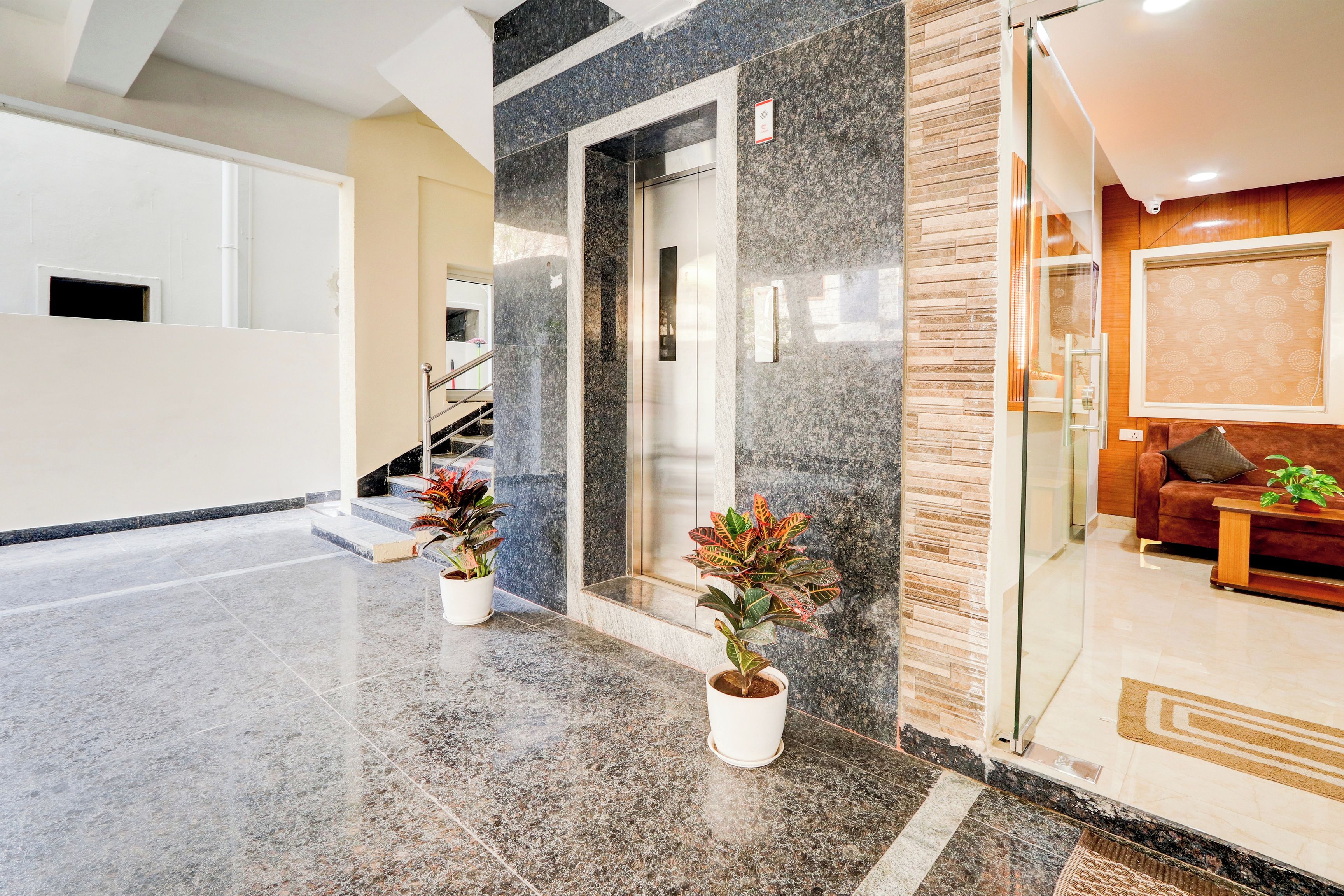 Un interior moderno con piso de mármol, una escalera y una sala de estar con sofá y mesa de centro.