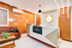 Una recepción con un cartel que dice 'TOWNHOUSE RECEPTION', un sofá con una planta y un aire acondicionado instalado en la pared.