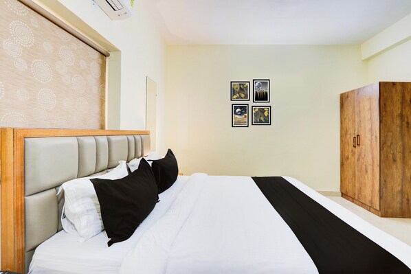 A hotel room with a bed, a wardrobe, and four framed pictures on the wall. - Townhouse Nirvana Elite (Hyderabad)