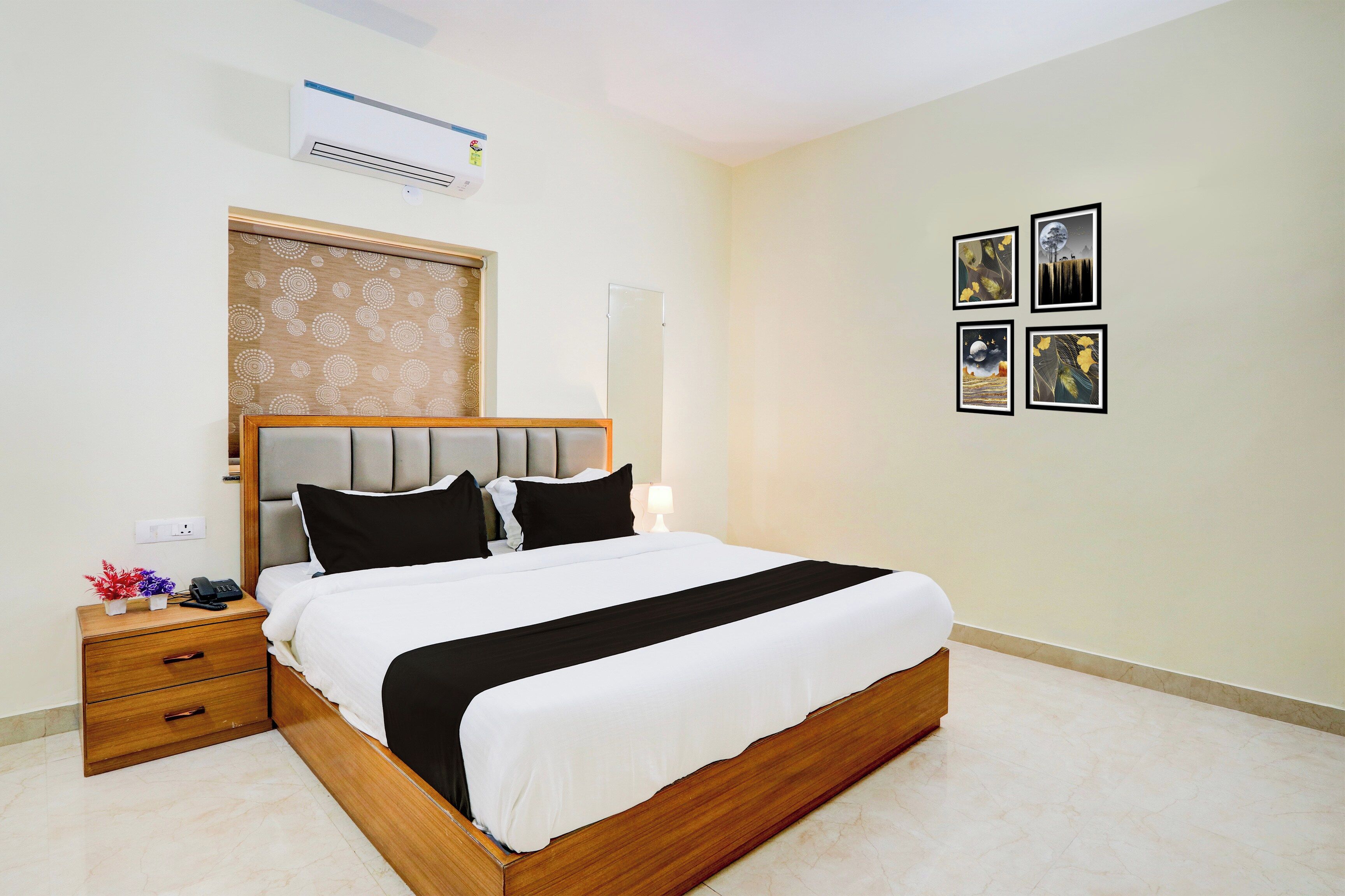 Habitación de hotel con cama, mesita de noche y aire acondicionado de pared.