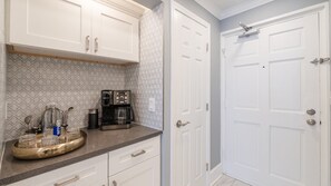 A kitchen with white cabinets, a coffee maker, and a stainless steel sink. - 404 Lighthouse Shores (Ponce Inlet)
