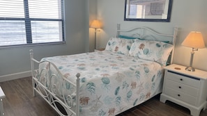 A bedroom with a bed, bedside tables, and a window with blinds. - #405 Sandcastle 2/2 Oceanfront Condo Traffic Free Beach (Ponce Inlet)