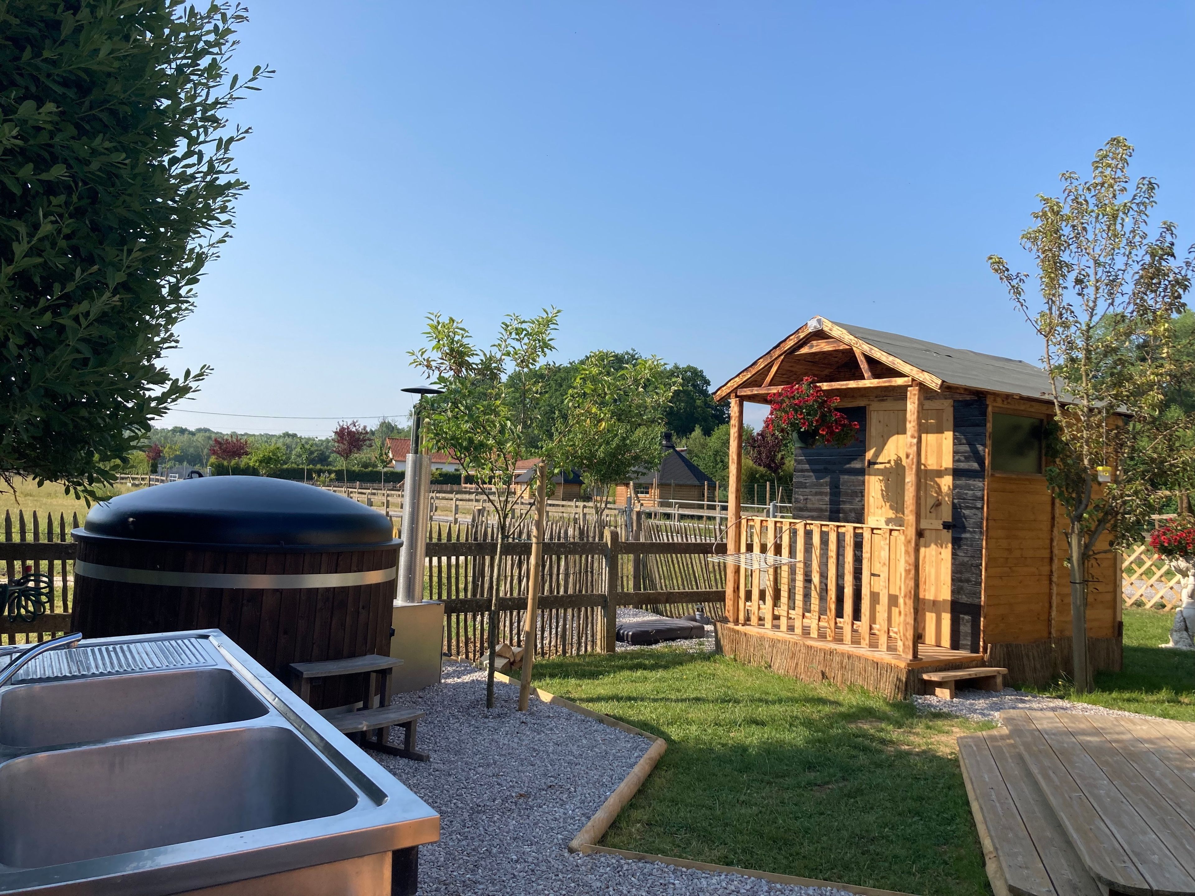 Un espace extérieur rustique, agrémenté d’une structure en bois, d’un barbecue et d’un évier en métal.