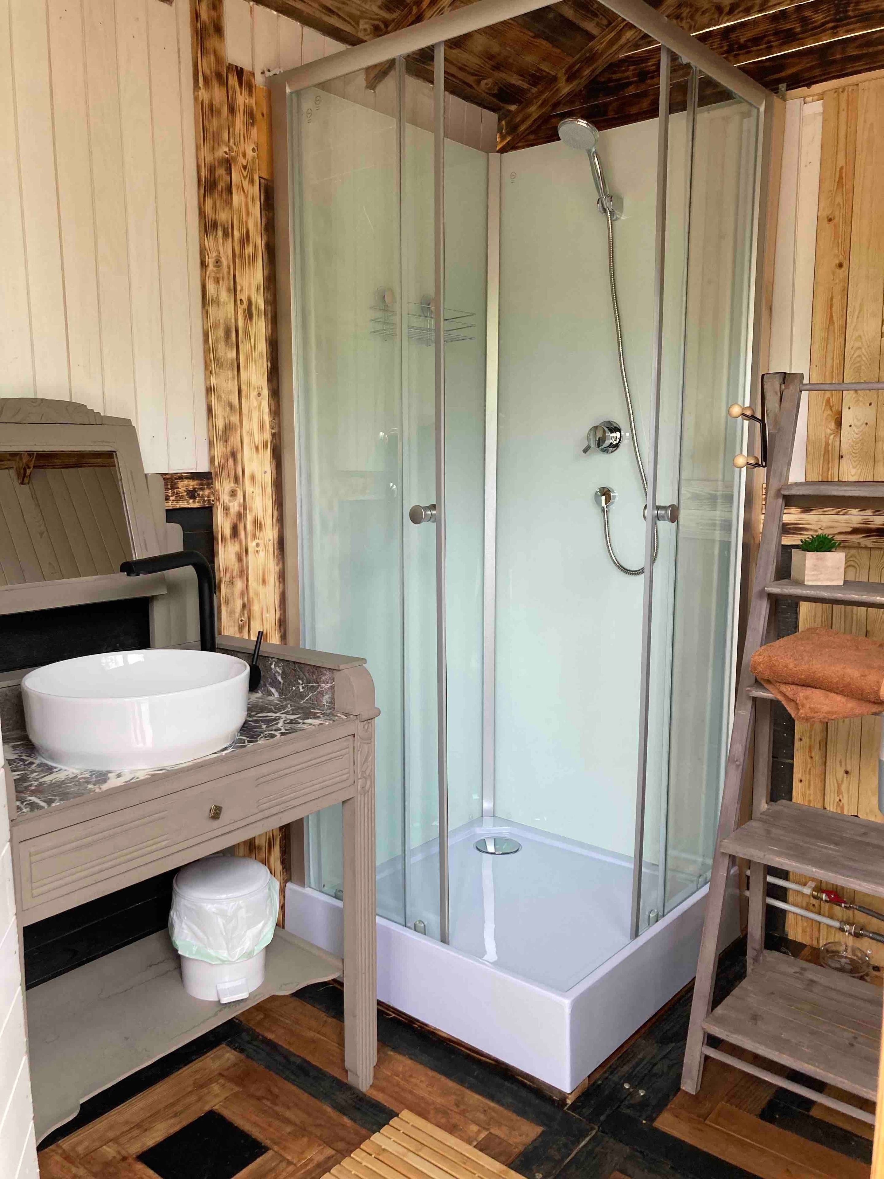 Une salle de bain avec une douche à parois de verre, un lavabo et un meuble-lavabo en bois.