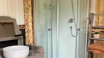Une salle de bain avec une douche à parois de verre, un lavabo et un meuble-lavabo en bois.