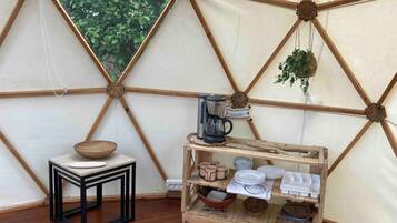 Een kamer met een houten trekwerkwand, een koffiezetapparaat, een houten kom en een klein tafeltje met een wit bord.