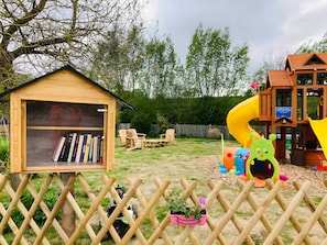 Ein hölzernes Spielhaus mit Bücherregal, Rutsche und Spielbereich mit Spielzeug.