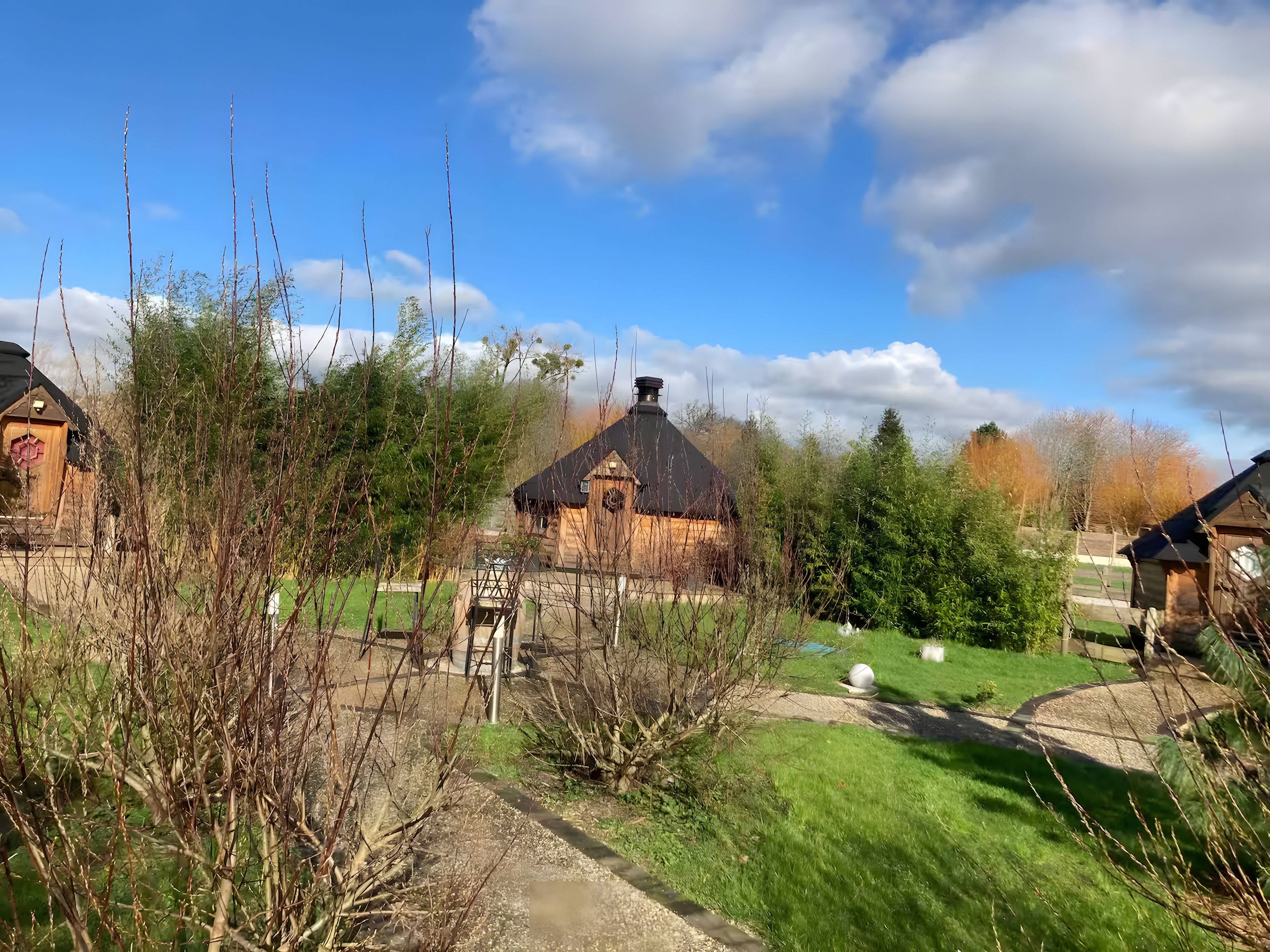 Een landelijk landschap met traditionele houten huizen, een heldere lucht en een verzorgd gazon.