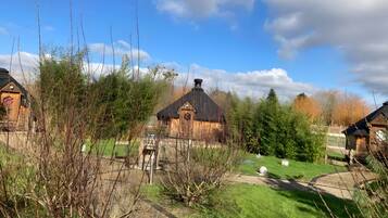 Een landelijk landschap met traditionele houten huizen, een heldere lucht en een verzorgd gazon.