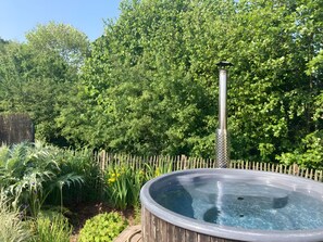 A hot tub surrounded by lush greenery and a wooden fence.
