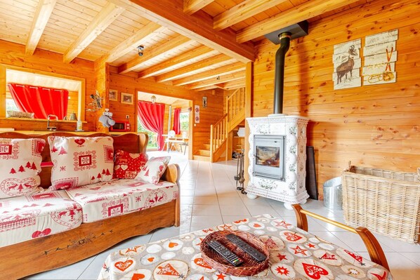 A cozy log cabin interior with a sofa, a fireplace, and a dining area.