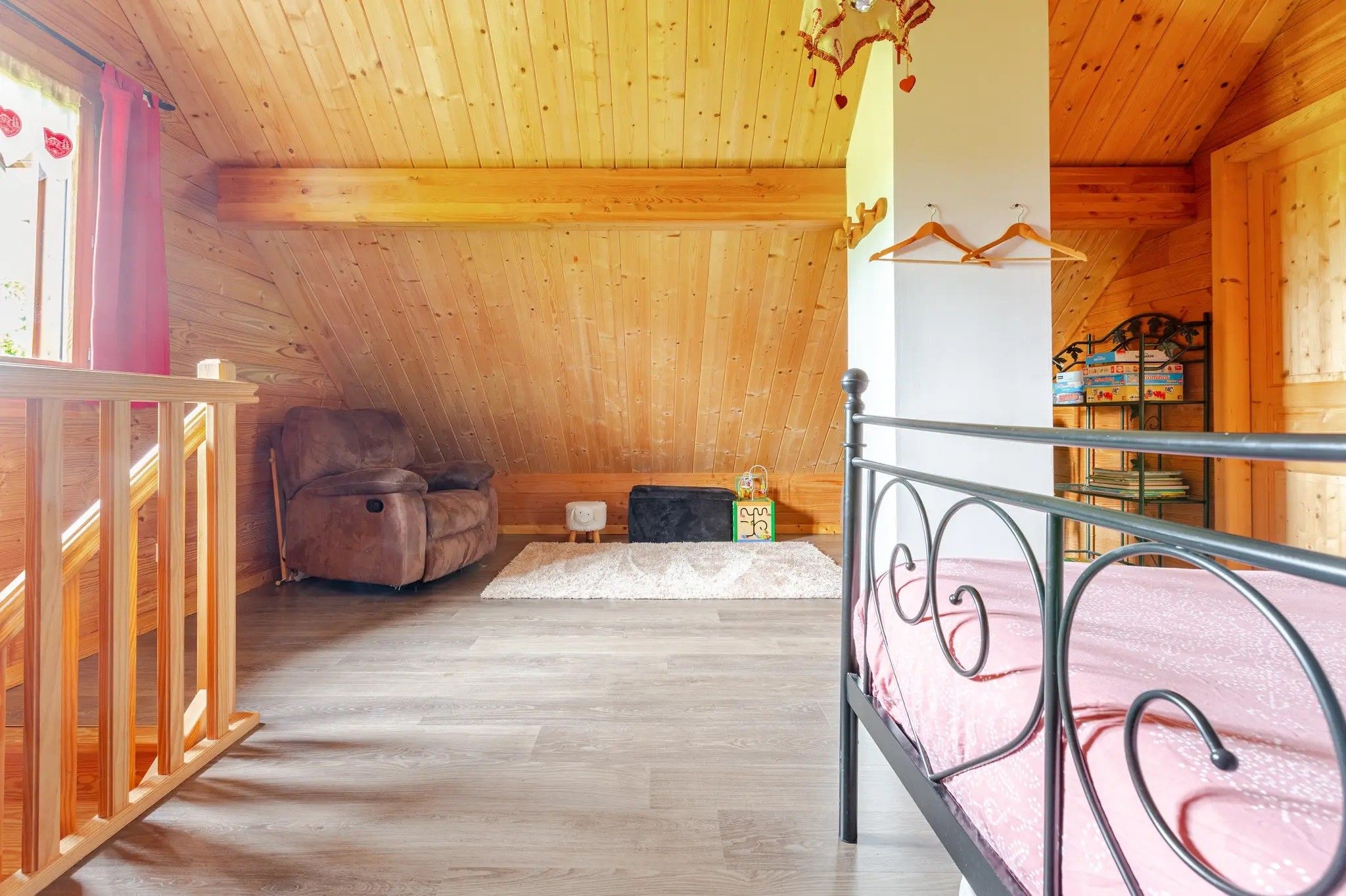 Een kamer met houten inrichting, een bed, een stoel en een klein tafeltje.