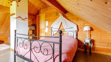 A bedroom with a canopy bed, wooden walls, and a sloped ceiling.