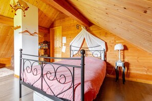 Un dormitorio con cama con dosel, paredes de madera y techo inclinado.