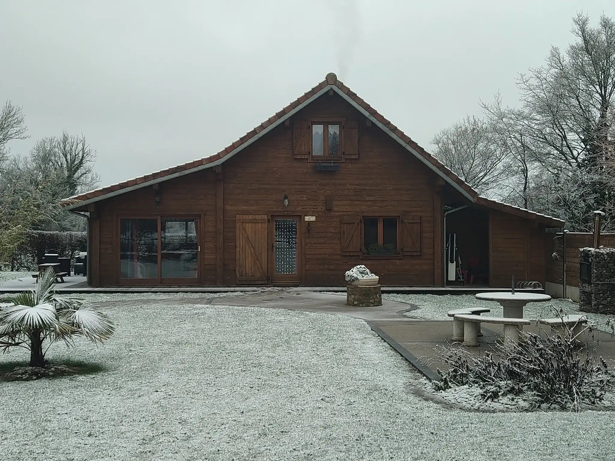 Een houten gebouw met een puntige daklijn, een voordeur en een groot raam.