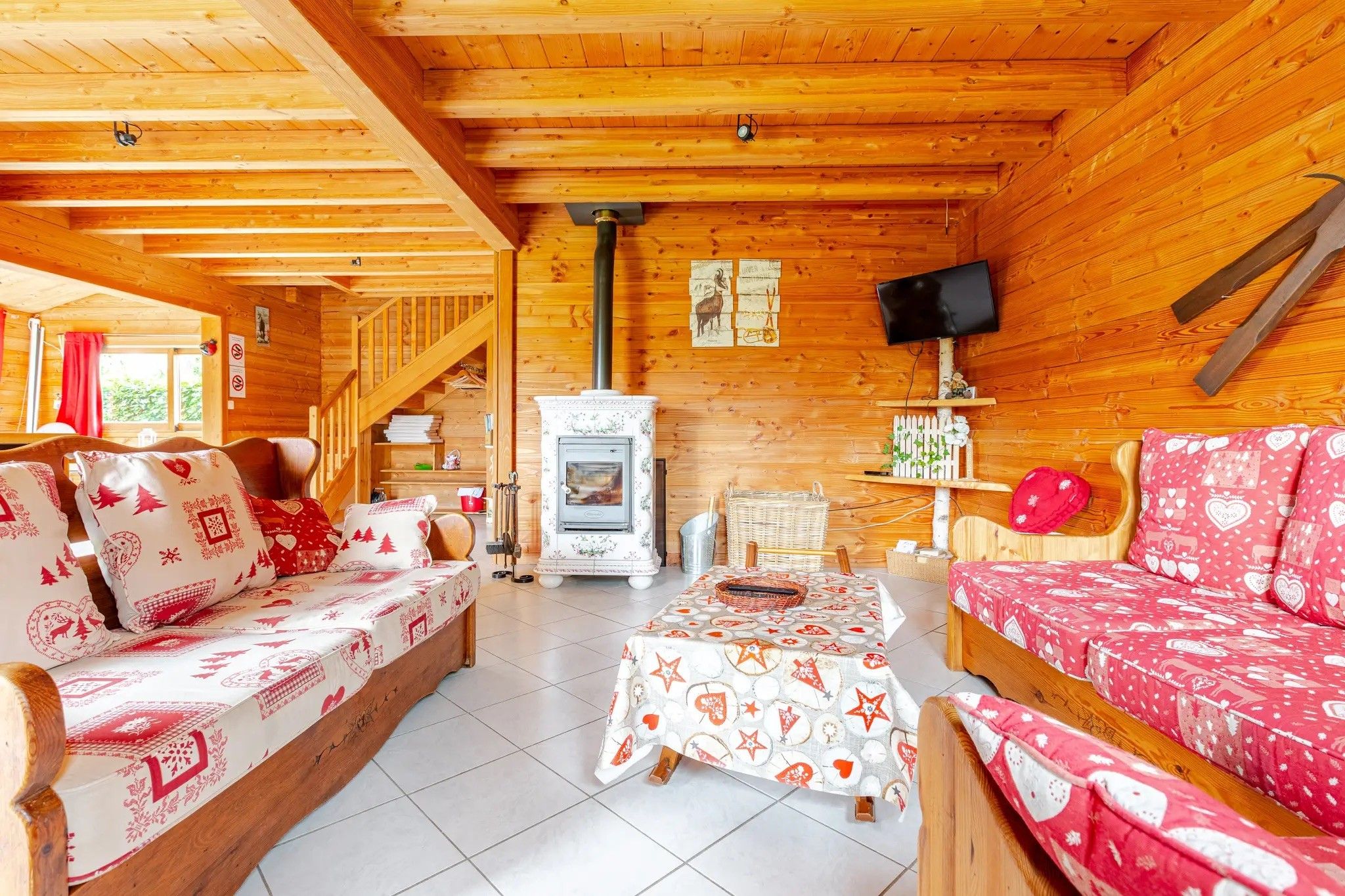 Een gezellig chaletinterieur met houten wanden, een open haard, een televisie en een eethoek.