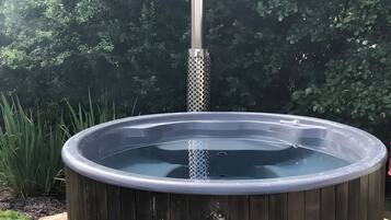 Een hottub met stoomfunctie, omringd door een houten terras en groen.