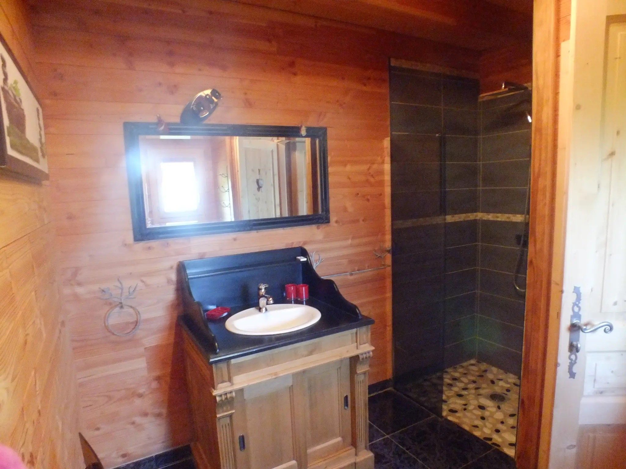 Une salle de bain en bois avec un lavabo, un miroir et une douche.