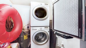 A laundry area with stacked washing machines and a large inflatable pool. - 406 Sandcastle in Ponce Inlet, FL (Ponce Inlet)