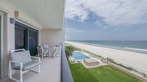 A balcony with a view of a beach and a pool. - 406 Sandcastle in Ponce Inlet, FL (Ponce Inlet)