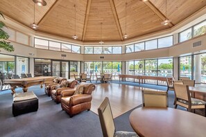 Un amplio espacio interior con techos altos, ventanas grandes y un área de descanso junto a la piscina.
