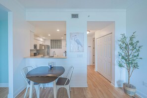A modern kitchen with white cabinetry, a dining table with two chairs, and a potted plant. - 4404 Harbour Village (Ponce Inlet)