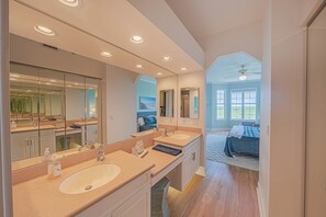 A modern bathroom with two sinks, large mirrors, and a ceiling fan. - 4404 Harbour Village (Ponce Inlet)