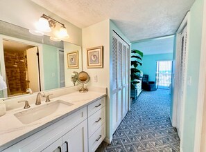 A bathroom with a double sink, a large mirror, and a walk-in closet with sliding doors. - #504 Tide Water Oceanview Condo (Ponce Inlet)