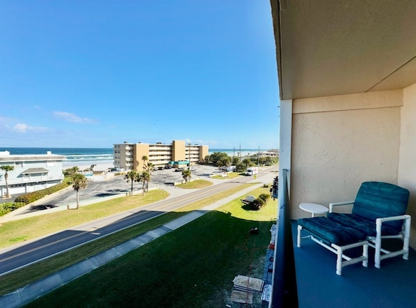A balcony with a view of the beach, a chair, and a small table. - #504 Tide Water Oceanview Condo (Ponce Inlet)
