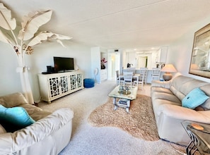 A living room with a sofa, coffee table, and a cabinet with a television. - #504 Tide Water Oceanview Condo (Ponce Inlet)