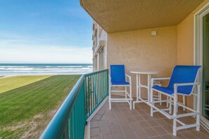 A balcony with a view of the ocean, two blue chairs, and a small table. - 5203 Towers in Ponce Inlet, FL (Ponce Inlet)