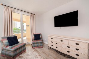 Une pièce comprenant un canapé, un téléviseur, une commode et une porte-fenêtre coulissante donnant sur un espace extérieur.