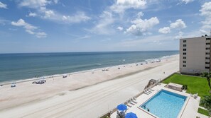 A beach view with a swimming pool and a building in the background. - 602 Sand Castle So in Ponce Inlet, FL (Ponce Inlet)