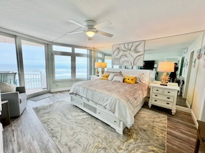 A bedroom with a large bed, a ceiling fan, a nightstand, a dresser, and a view of the ocean. - #604 Blue Surf 2/2 Oceanfront Condo On Traffic Free Beach (Daytona Beach Shores)