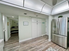 A modern kitchen with a stainless steel refrigerator, a wooden floor, and a door labeled 'BEACH HOUSE'. - #604 Blue Surf 2/2 Oceanfront Condo On Traffic Free Beach (Daytona Beach Shores)