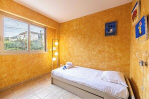 A bedroom with a bed, a window, a wall-mounted light fixture, and a painting. - Family Apartment with Pool & Garden 5 P - Cannes (Cannes)