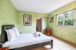Une chambre avec un lit, une armoire, une douche et une fenêtre donnant sur un espace verdoyant.