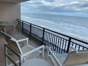 A balcony with a view of the ocean, equipped with a table and chairs. - #604 Sandcastle 2/2 Oceanfront condo - Traffic Free Beach (Ponce Inlet)