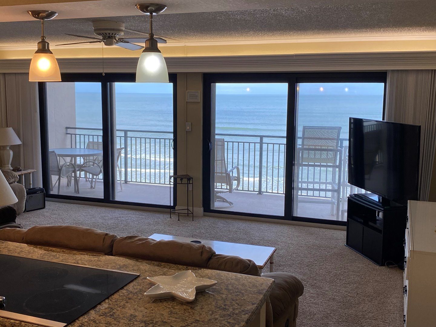 A hotel room with a balcony, a television, and a dining area with chairs and a table.
